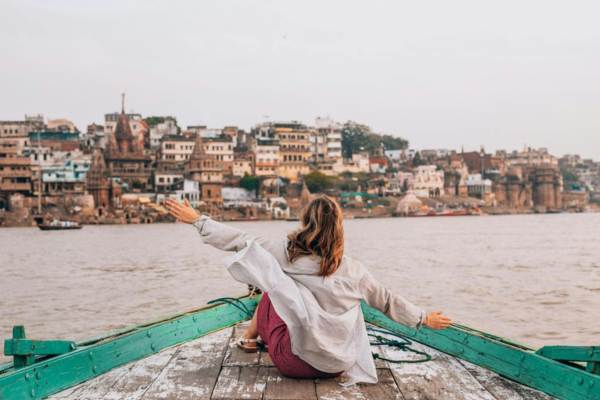 Tourists walking along the ghats of Varanasi during daytime, showing a busy yet safe travel environment near the Ganges River.